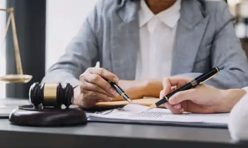 A social security disability lawyer in a grety suit pictured behind a desk.