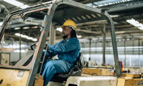 A construction worker drives a forklift.